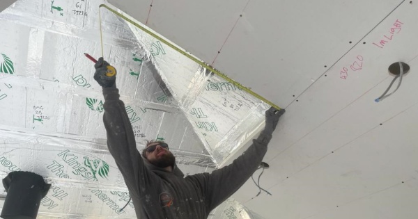 A man measuring the insulated plasterboard for a conservatory roof conversion 2