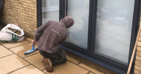 Construction worker cleaning conservatory windows after a conservatory roof conversion