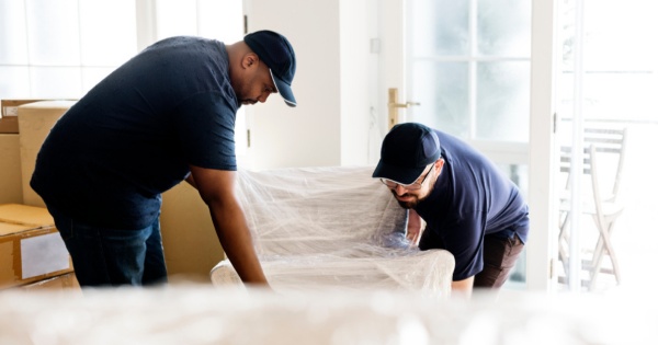 Two men protecting and moving furniture before a conservatory roof conversion