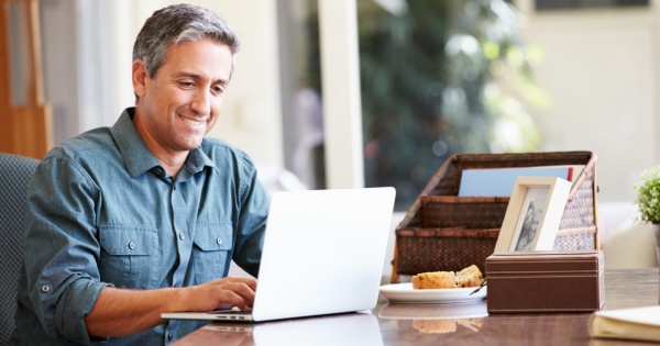 Happy man working on his desk searching for conservatory roofing options