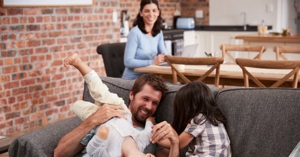 Father plays with children in playroom while mother works in the back since they converted their conservatory into an open plan living room.