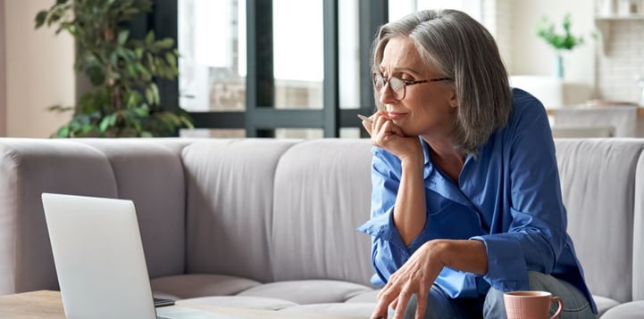 Grey-haired woman searching the internet to understand if condensation in her conservatory is normal