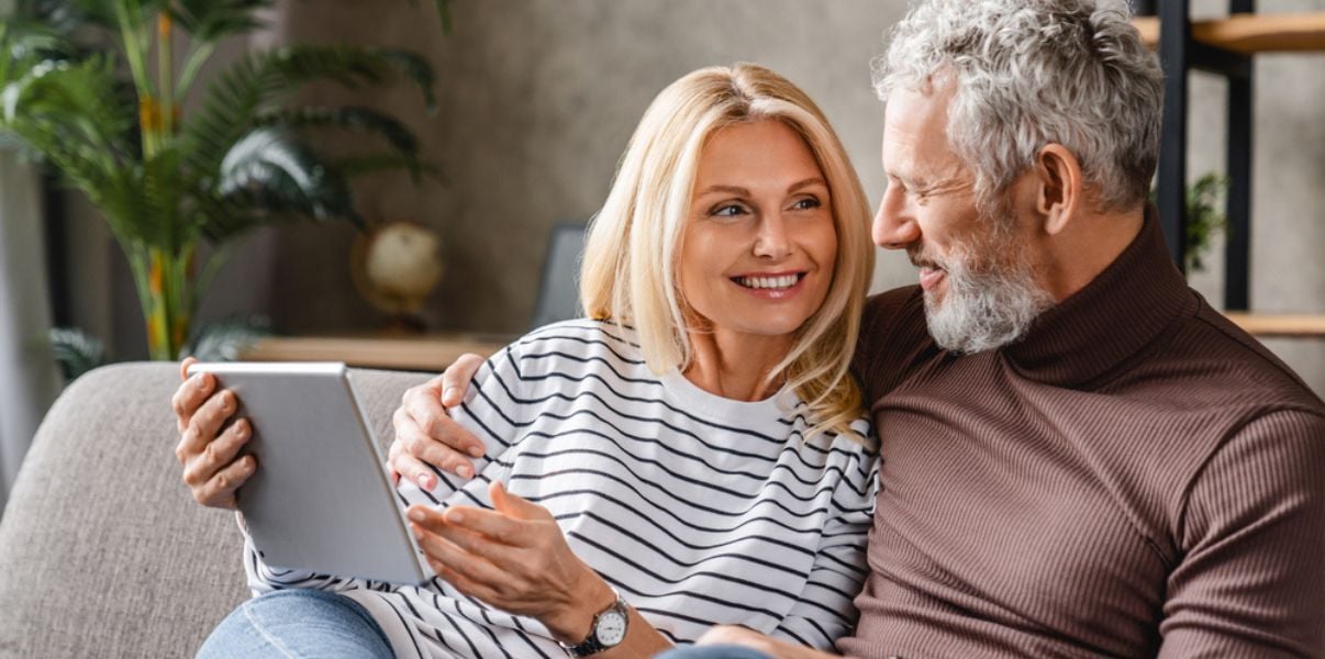 Middleaged couple reading Projects4Roofings blog on how to take care of their new conservatory roof