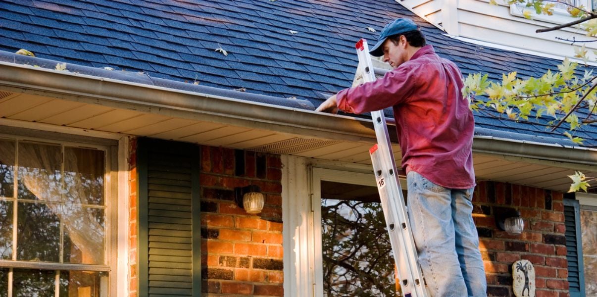 Middleaged man cleaning the gutters on his conservatory roof