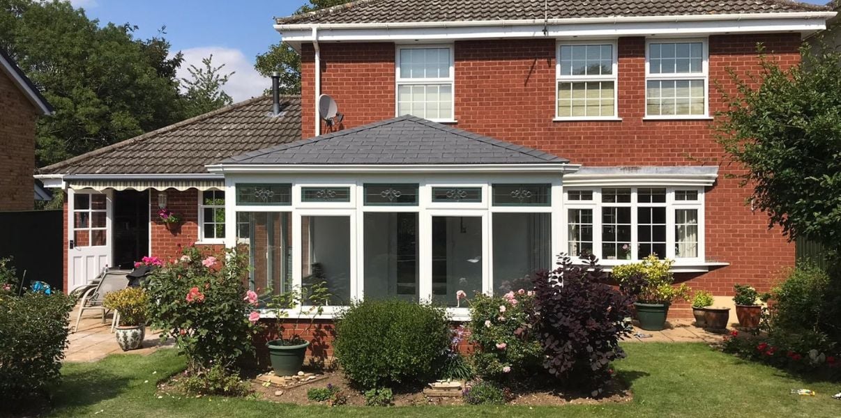 Lovely conservatory with a solid roof sorrounded by flowes