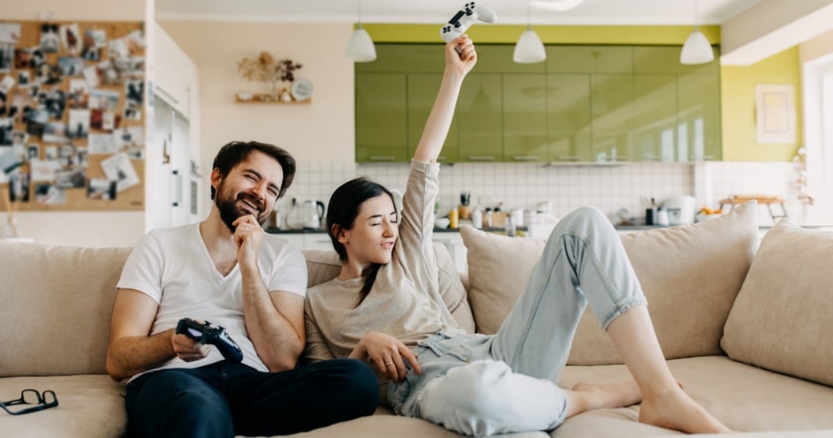 Young couple playing video games after having a conservatory transformation 