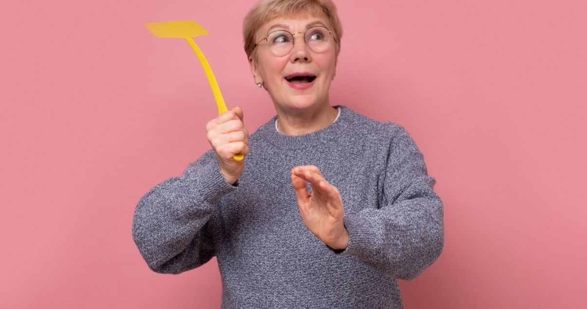 Woman with a fly swatter killing flies in her conservatory